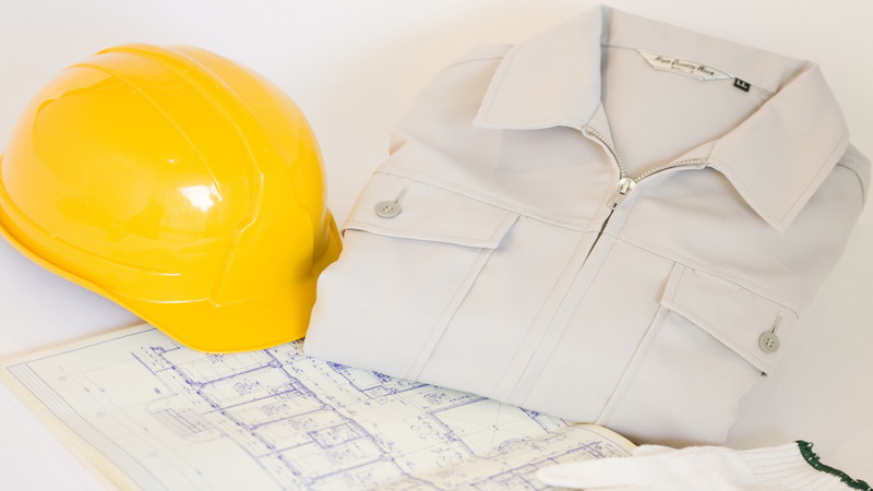 黄色いヘルメットと作業服と設計図